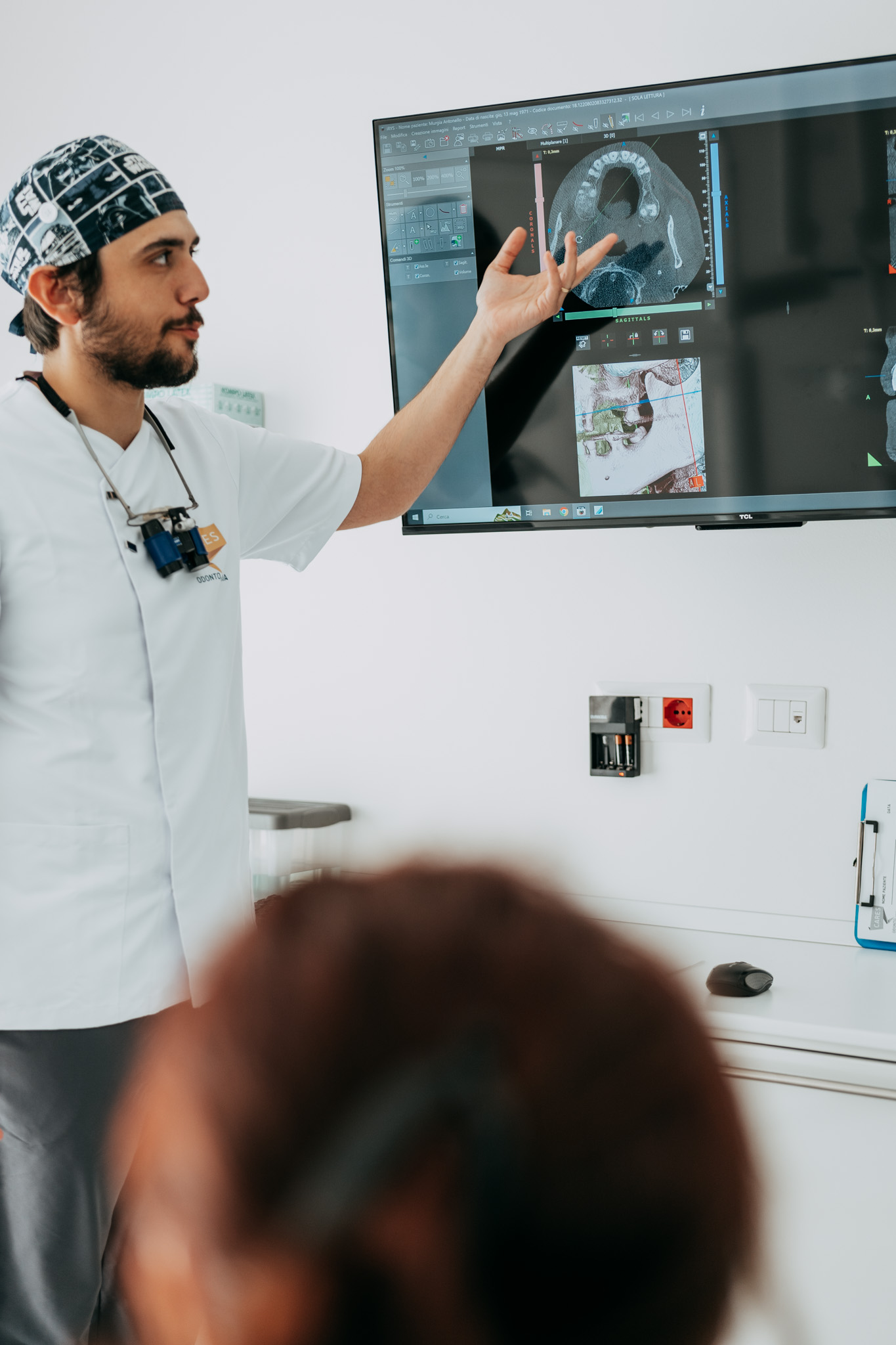 Dentista di Cares Odontoiatria Uta mostra una radiografia digitale a un paziente durante la consulenza, studio vicino a Siliqua