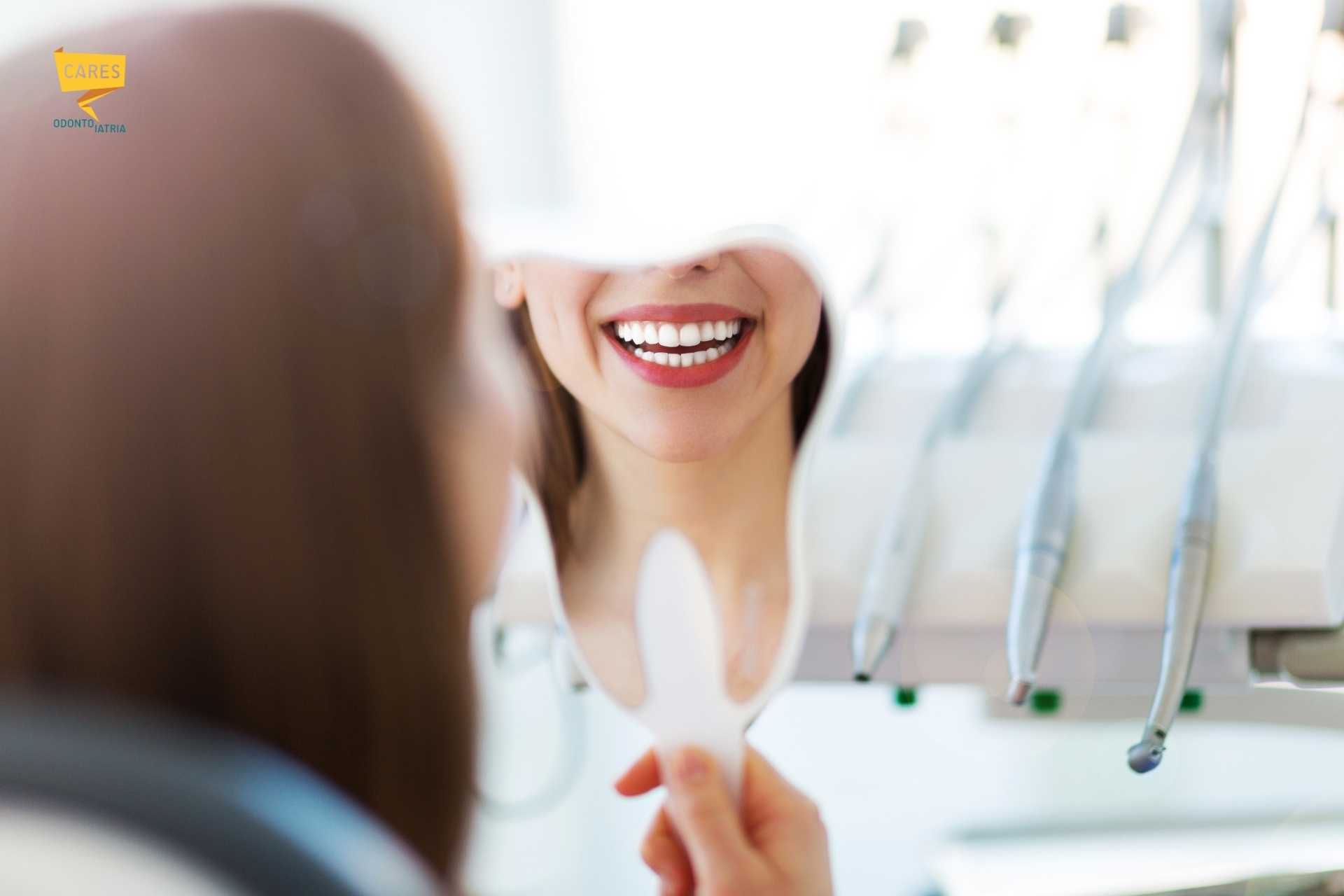 Paziente che sorride guardandosi allo specchio dopo un trattamento di implantologia dentale presso Cares Odontoiatria Uta, vicino a Villasor