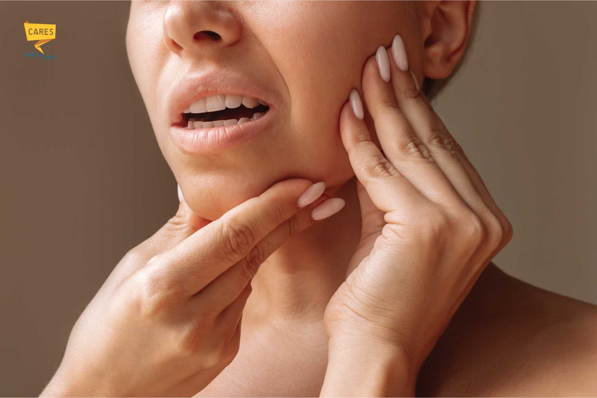 Donna che tocca la mandibola con le mani per il dolore, segno di possibile disfunzione articolare o problema ai muscoli della mascella.