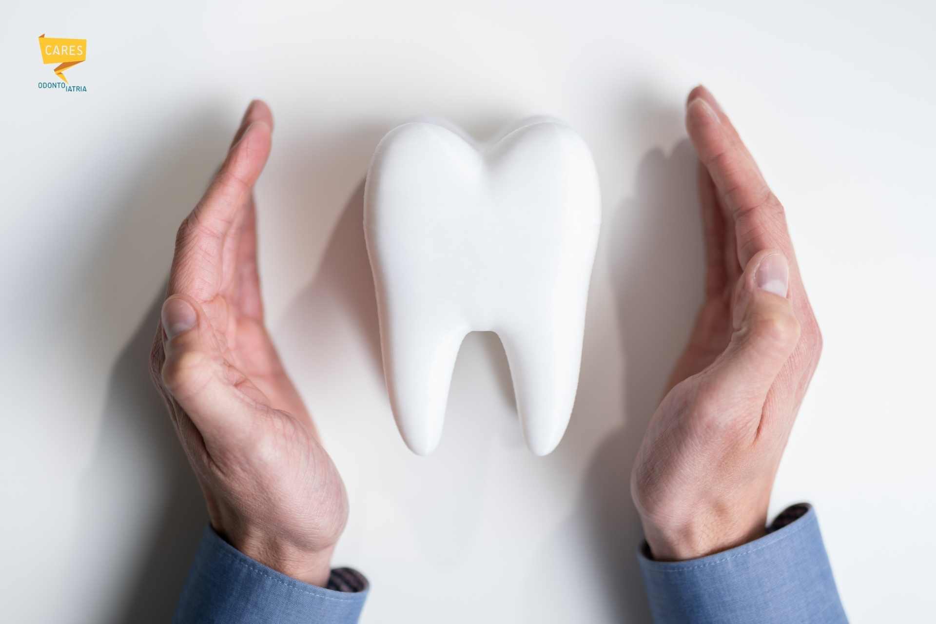 Protezione del dente devitalizzato Mani che proteggono un modellino di dente devitalizzato su sfondo chiaro